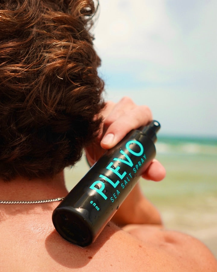 Working the spray through the back of damp hair, ocean behind